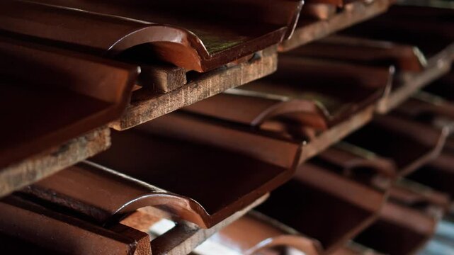 An Indonesian factory producing red clay roof tiles using ancient technology on the island of Bali. Many products are left on drying shelves.