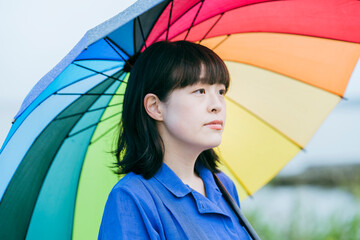 雨の中、カラフルな傘を指す女性