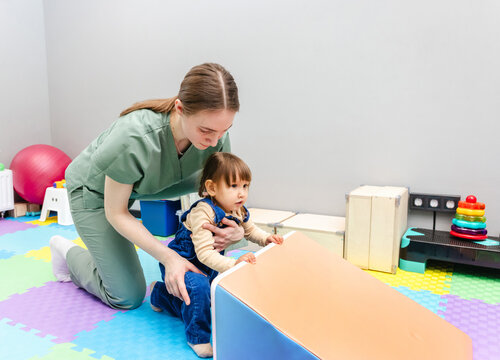 Neurological rehabilitation for child with therapeutic physiotherapy. Physiotherapist assisting young child with coordination exercise in rehab center