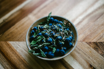 Blueberry and Herbs in a Pottery Bowl Against a Wooden Background