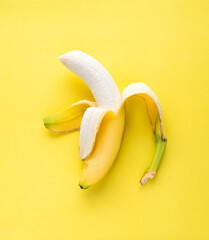 Top view of single partially peeled banana on yellow background. © Cavan