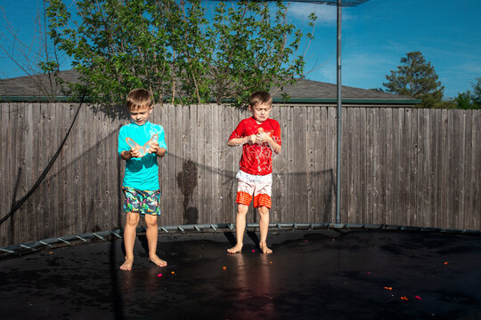 Two boys breaking water balloons on a trampoline
