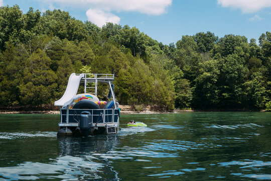 Woman floating next to pontoon boat in lake on summer day