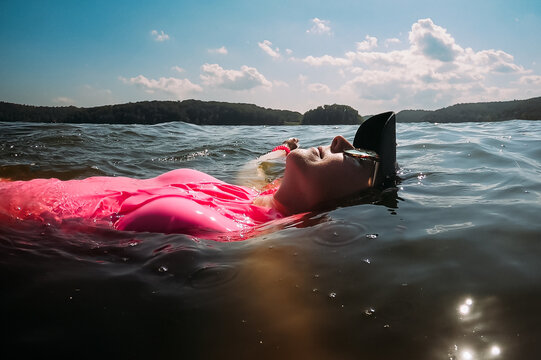 Woman floating on back in lake in summertime sunshine
