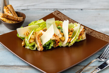Chicken Caesar salad served on a porcelain plate with crusty bread