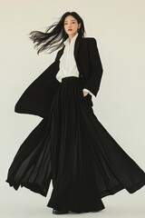 Wind-swept elegance. A woman in black and white, framed against a minimalist backdrop. Effortless style and graceful movement