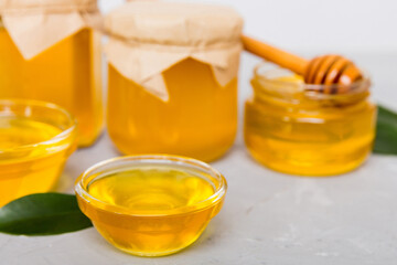 Honey in jar with leaves and honey dipper on colored background top view with copy text