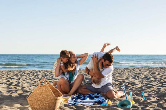 Happy family playing together on the beach during summer vacation