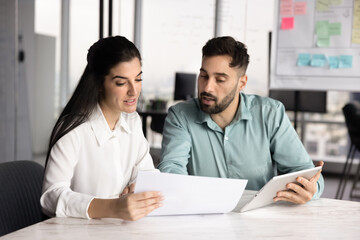 Focused busy male and female managers reading legal paper documents, analyzing sales financial...