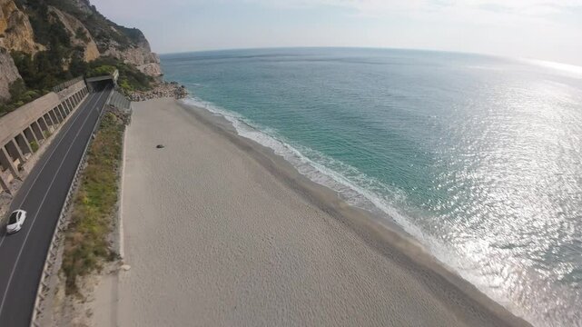 downward FPV aerial dive and skim across the majestic turquoise waters of Spiaggia del Malpasso beaches glistening in the sun