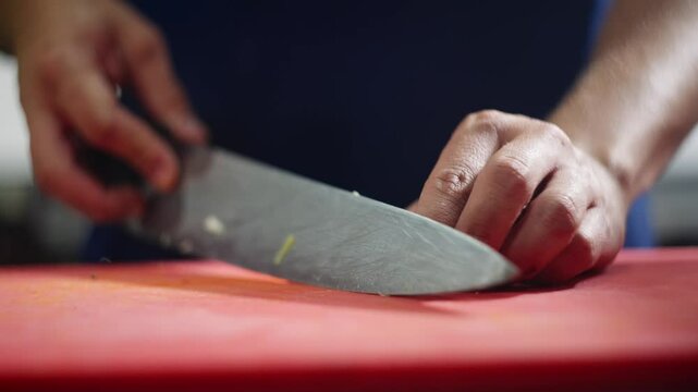 Close up view of a chef quickly cutting celery sticks in julienne over a board.