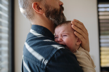 Father comforting his crying baby son.