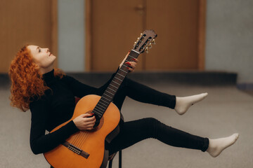 Red-Haired Woman Playing Guitar While Sitting in a Unique Pose