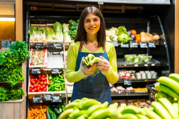 Saleswoman holding bananas in organic supermarket or grocery store