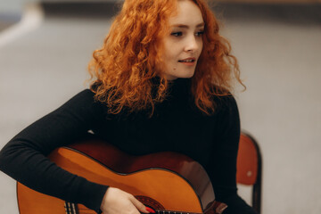 Young Woman Sitting and Playing Acoustic Guitar with a Thoughtful Expression