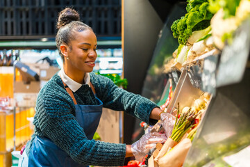 Saleswoman arranging fresh organic vegetables on display in supermarket
