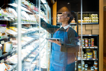 Saleswoman checking food products using digital tablet in organic supermarket