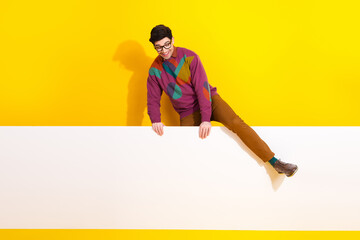 Stylish man wearing colorful sweater posing with cheerful expression against bright yellow background, representing creativity