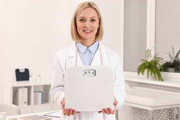Weight loss. Happy nutritionist with scales in clinic