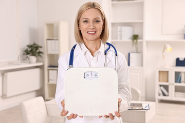 Weight loss. Smiling nutritionist with stethoscope and scales in clinic