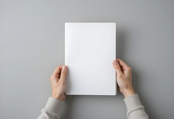 Hands holding white blank paper sheet mockup isolated on gray background