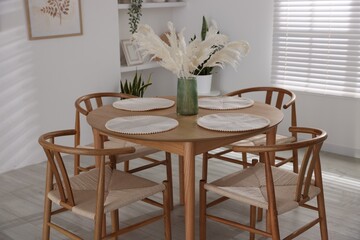 Stylish wooden table with chairs and decor indoors. Interior design