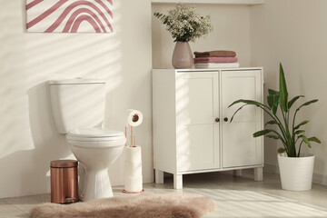 Fototapeta premium Ceramic toilet bowl, houseplants and necessities in restroom