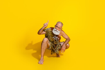 Full size photo of ancient aged caveman direct finger up empty space wear leopard skin clothes isolated on yellow color background
