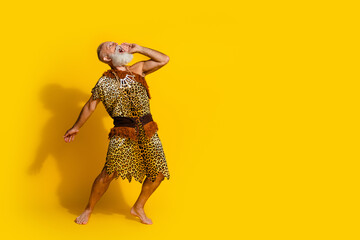 Full length photo of handsome cool neanderthal guy wear leoprad skin yelling emtpy space isolated yellow color background