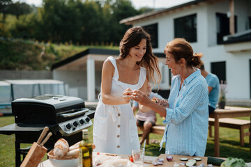 Adult daughter and mother preparing food for a family barbecue.