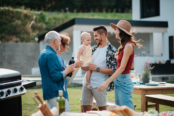 Parents welcoming their son, daughter-in-law, and baby at a family barbecue.