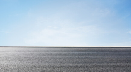 Empty asphalt road under a clear blue sky