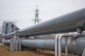 pipeline and power transmission tower against gray sky