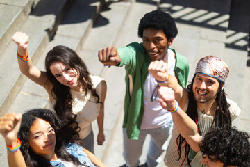 Young activists raising fists showing rainbow bracelets at pride parade