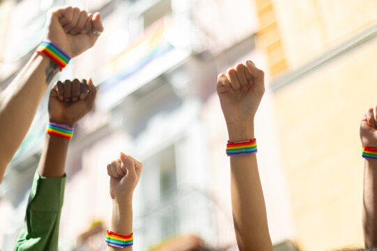 Activists raising fists wearing rainbow bracelets at pride parade
