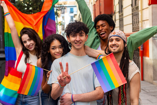 Young activists showing rainbow flags and peace sign at pride parade