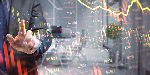 Businessperson analyzing stock market data with candlestick chart overlays on transparent screen in modern office background.