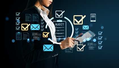 Businesswoman using digital tablet with audit checklist icons and technology symbols on dark background illustrating business concept.