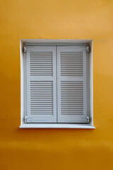 Fototapeta premium Classic Grey Shutter on a Rustic Yellow Wall, Evoking Mediterranean Charm