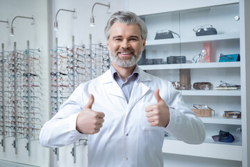 Fototapeta premium Bearded caucasian man in lab coat at his working place in optic shop
