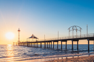 Fototapeta premium Brighton Jetty with people at sunset while viewed from the beach at sunset time, South Australia