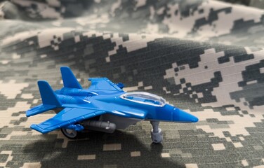 Blue Fighter Jet Toy on Camouflage Background
