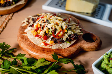 close up view of mexican taco with black beans, known as frijoles negros, with mais ketchup, cheese and mayonnaise sauce on wooden table