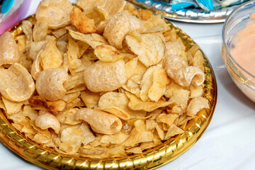 Close-up of a plate filled with chips and pork rinds, typical of junk food. These products, rich in saturated fat, sodium, and empty calories, 