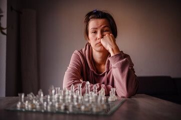 Woman in Hoodie Deep in Thought During Chess Game