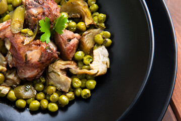 Stufato di carne di maiale con piselli e carciofi, cibo italiano 