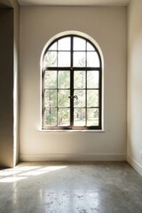 Fototapeta premium Sunlight streams through an arched window, illuminating a minimalist room with a polished concrete floor