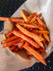 Close-up of long, crispy sweet potato chips on a cafe table. Fast food snack