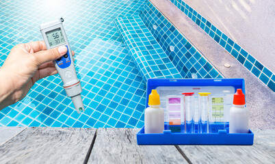 Digital water tester technology with Water tester test kit on wooden table over blurred resort swimming pool background, swimming pool service and maintenance