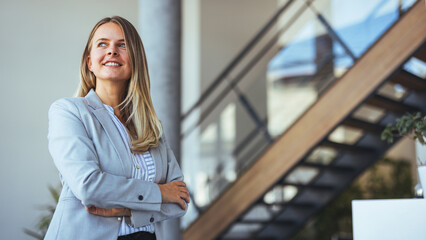 Confident Businesswoman Standing in Modern Office Interior Near a Staircase